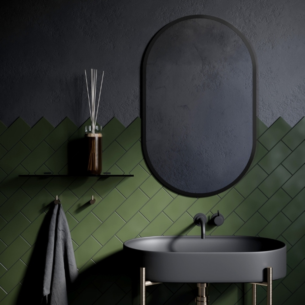 Lifestyle image of the Origins Living Docklands 500mm x 800mm Black Capsule Mirror mounted on black and green wall, in-front of a modern, grey coloured basin. DKL-00C058-BK